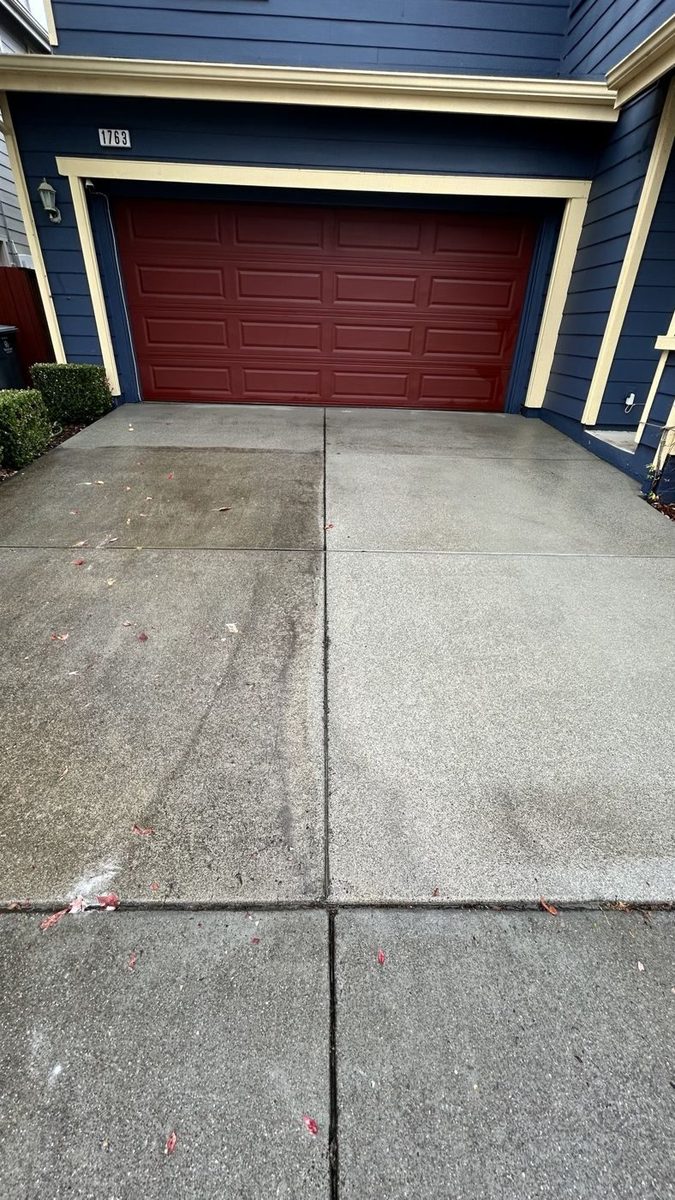 Concrete driveway half pressure-washed, dirty side next to clean side