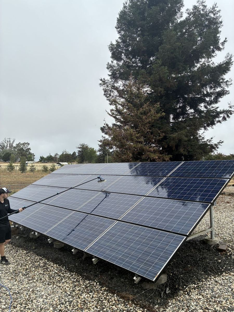 G&J tech cleaning a ground-mount solar array with a water-fed pole